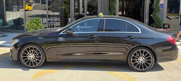 Black Mercedes E-Class taxi in profile outside a Split hotel entrance